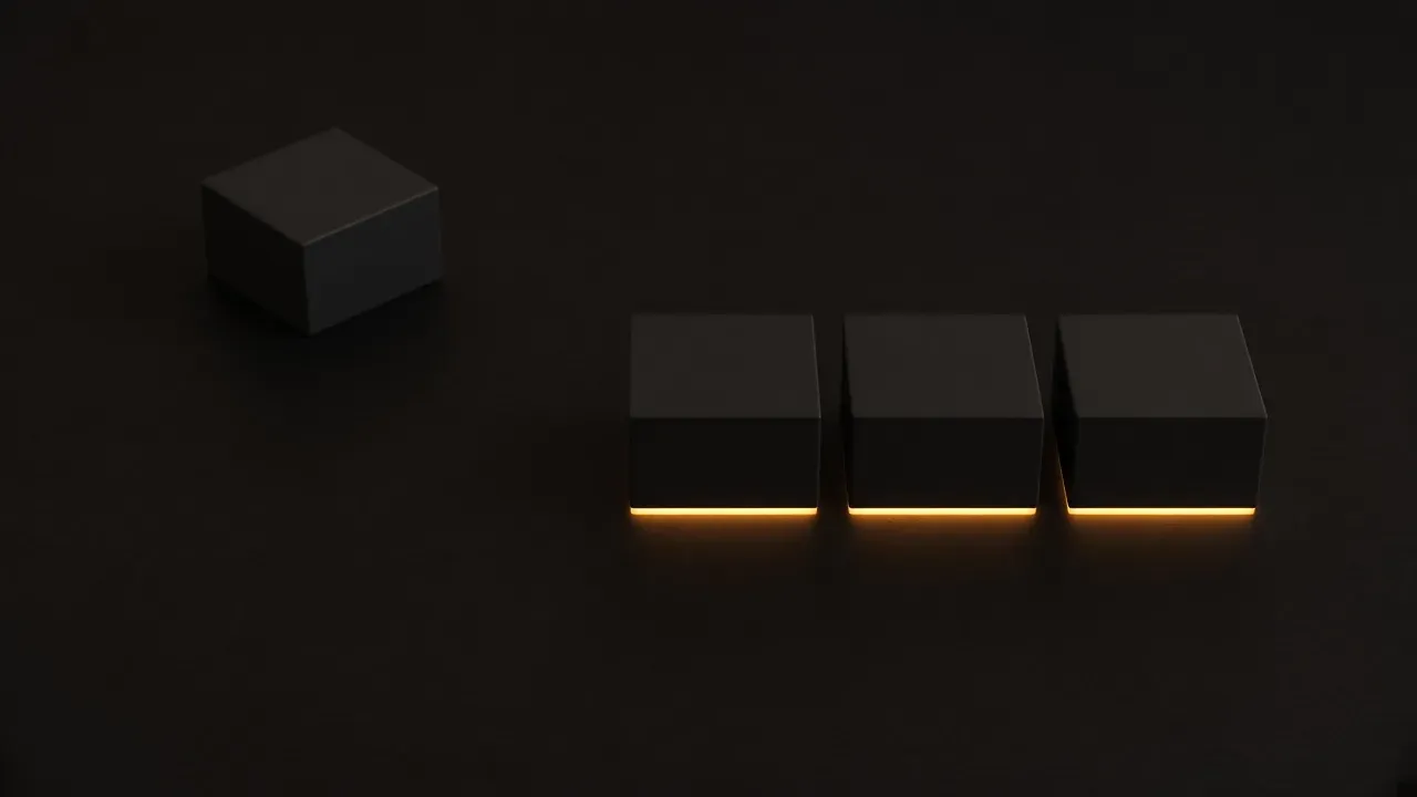 Three matte black cubes in a row on a dark surface, each with a warm line along its near edge, and a fourth cube set apart to the left