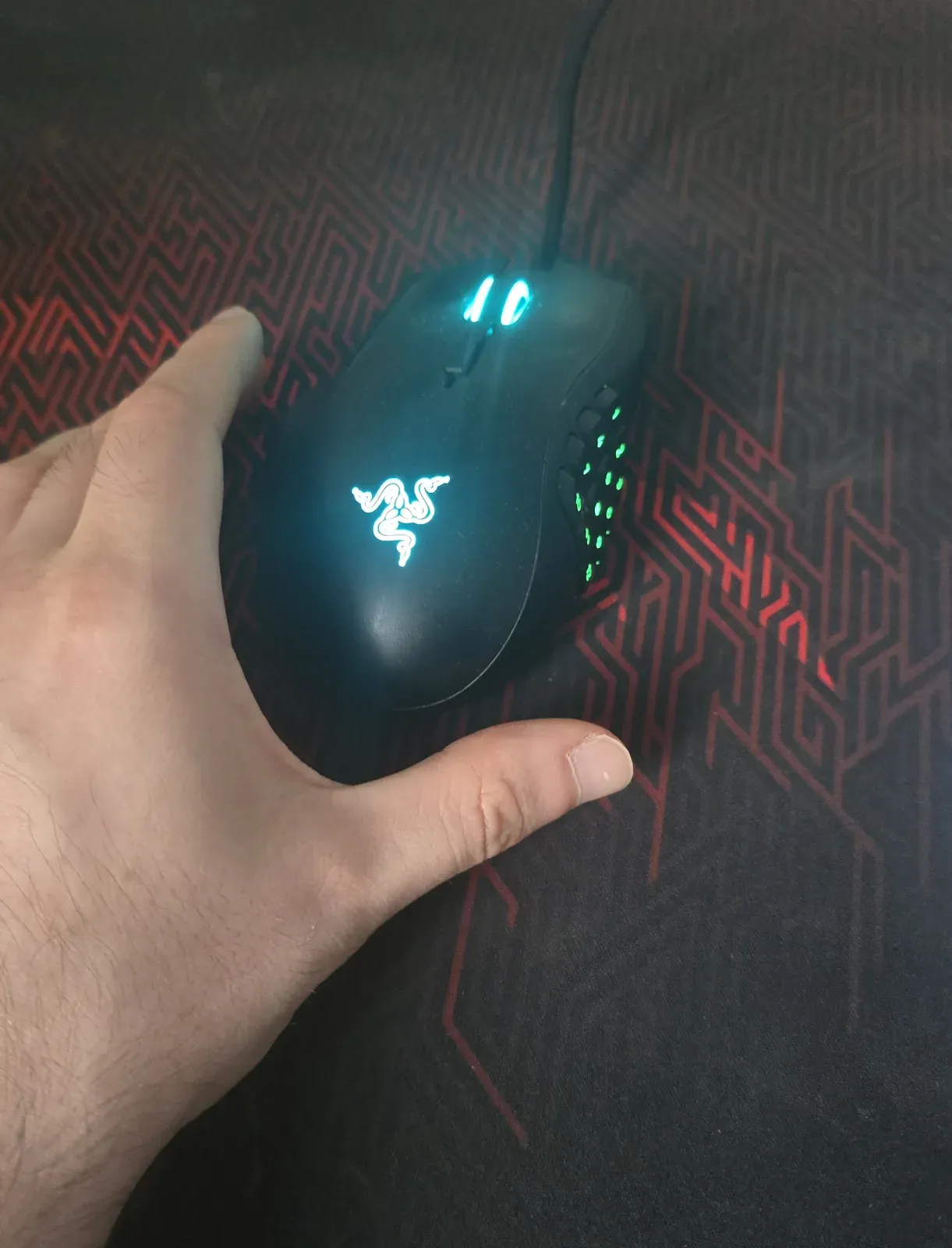Black Razer Naga Left-Handed Edition from above, with its green-lit 12-button thumb grid on the right side under a left hand