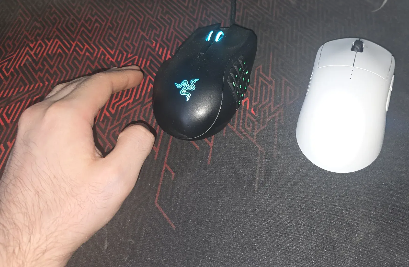 Razer Naga Left-Handed and Logitech PRO 2 LIGHTSPEED side by side on a mouse pad, with a left hand resting beside the Naga
