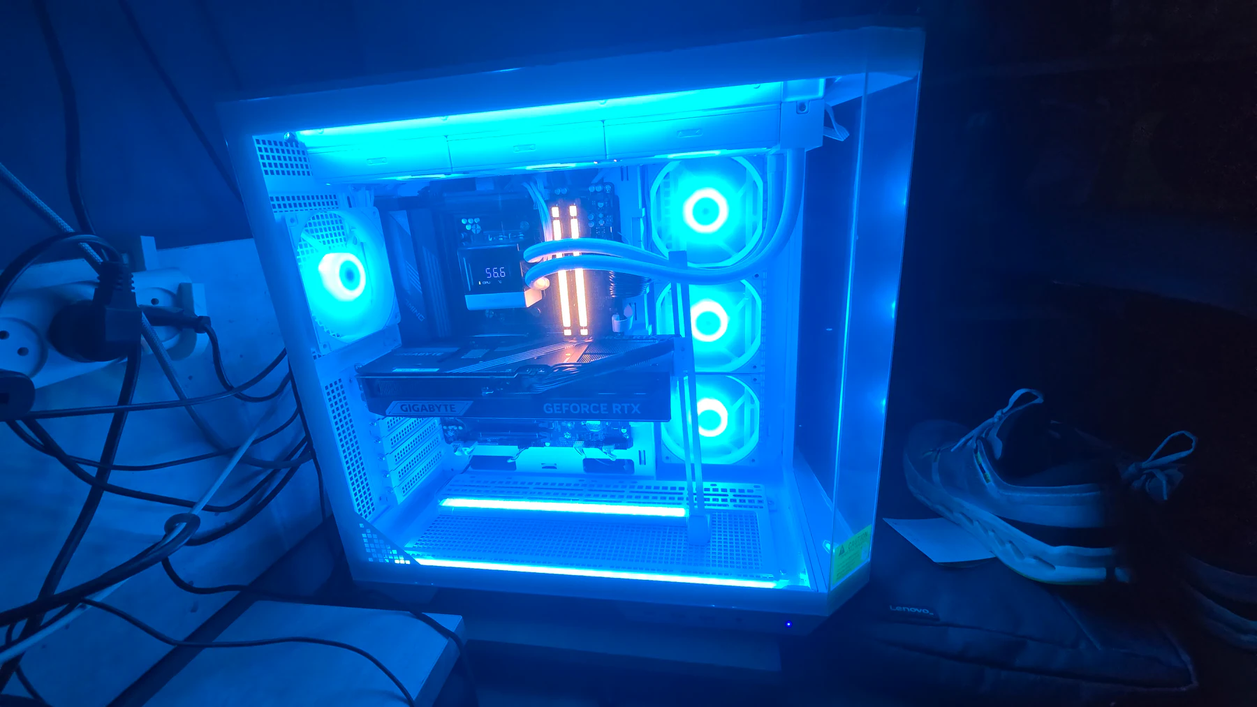 Yuval's white glass PC case lit blue, showing a Gigabyte GeForce RTX graphics card, AIO cooler tubes, and RGB fans